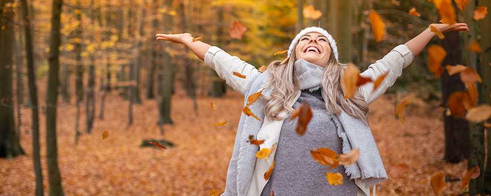 Persoon in bos met herfst en gooit met blaadjes