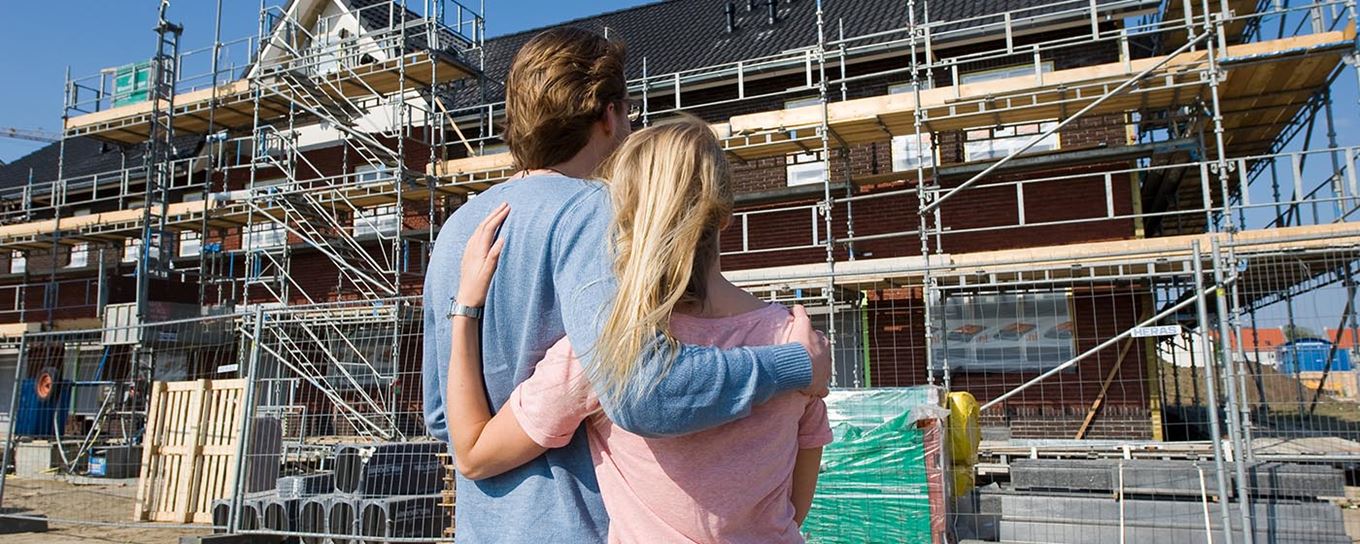 Jong stel kijkt naar hun nieuwe huis in aanbouw | a.s.r. doet het