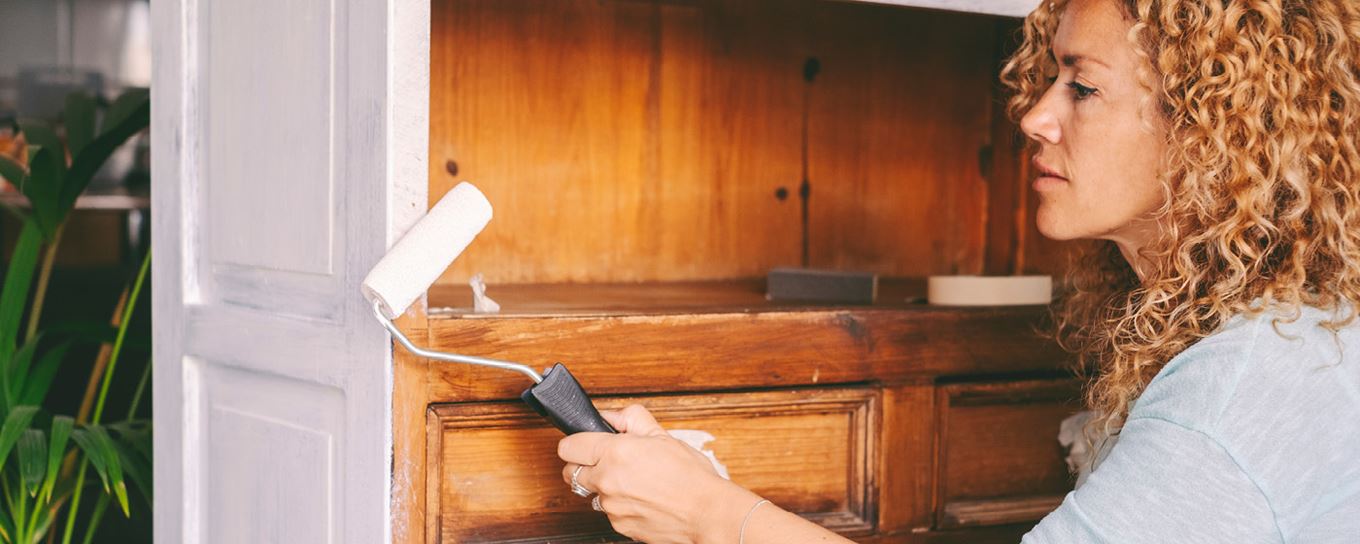 Jonge vrouw verft een oud kastje | a.s.r.