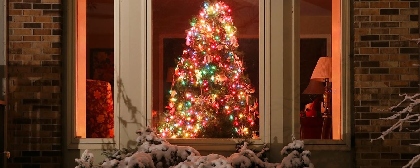 Versierde kerstboom vanuit buiten door het raam bekeken