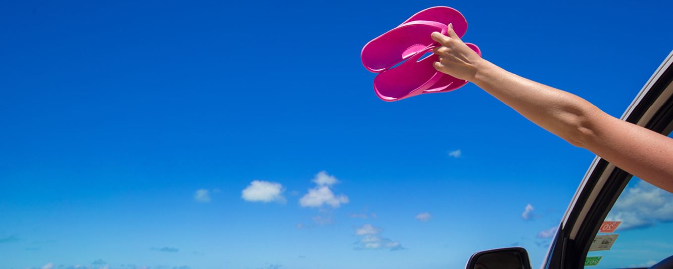 Hand uit een auto met daarin roze slippers | a.s.r.