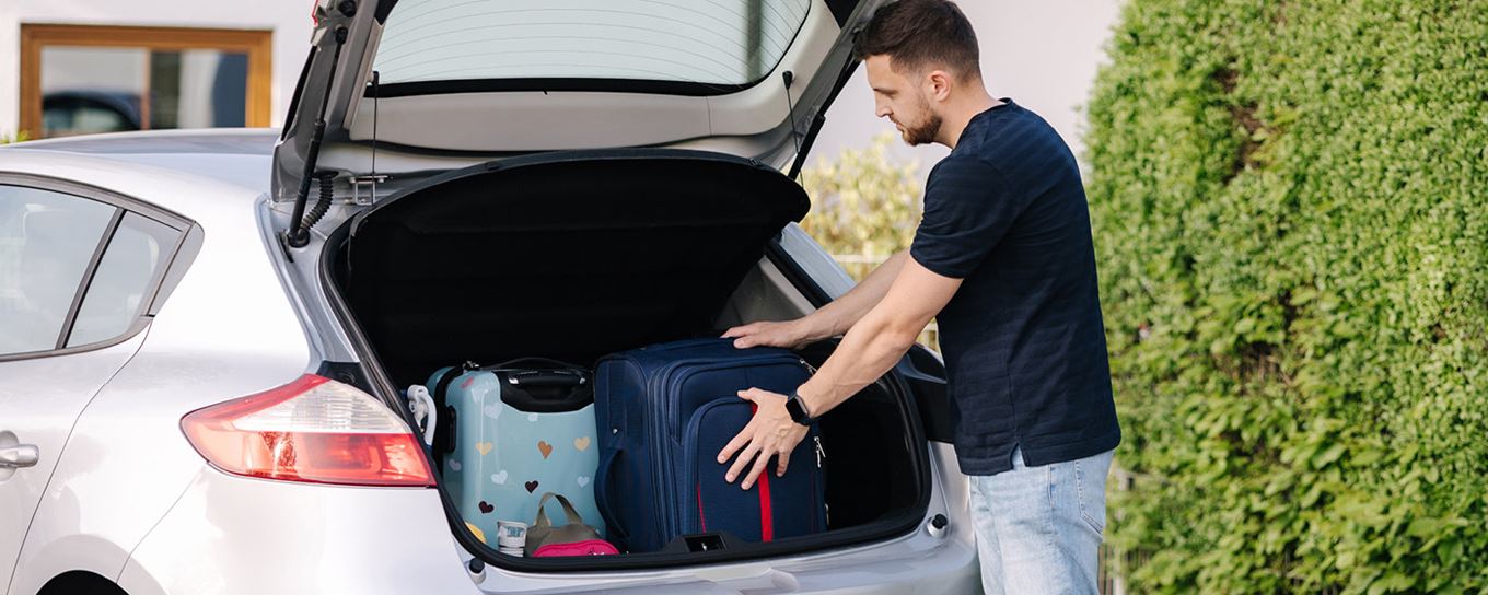 Man plaats vakantiespullen in de achterbank van de auto | a.s.r.