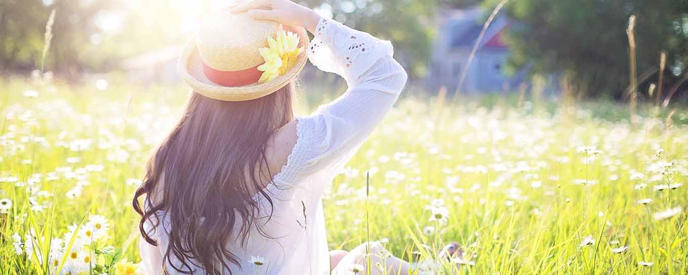 Jonge vrouw met een zomerhoed op in het hoge gras | Dit is de tijd van doen | a.s.r.