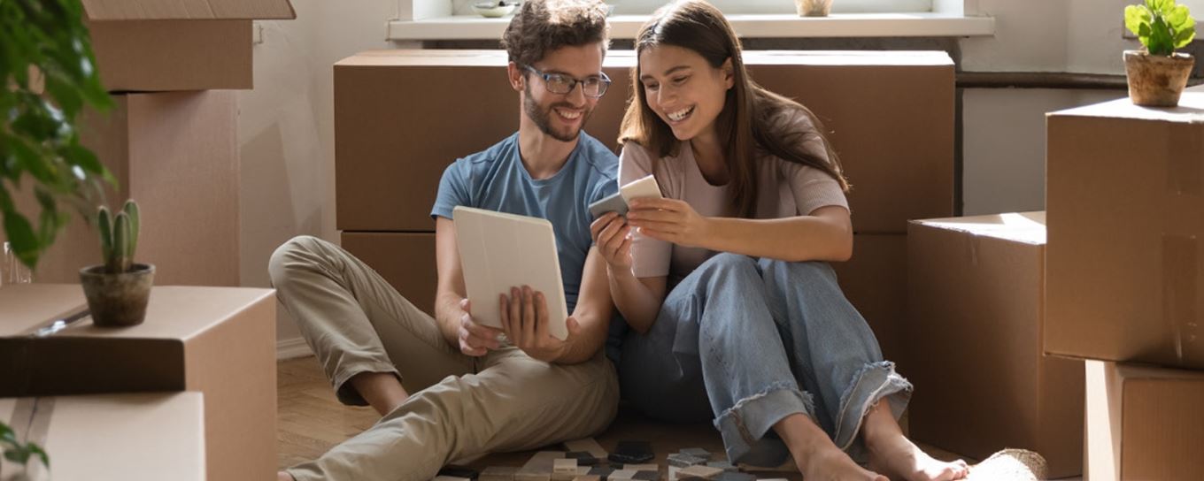 een jonge man en vrouw zitten tussen verhuisdozen