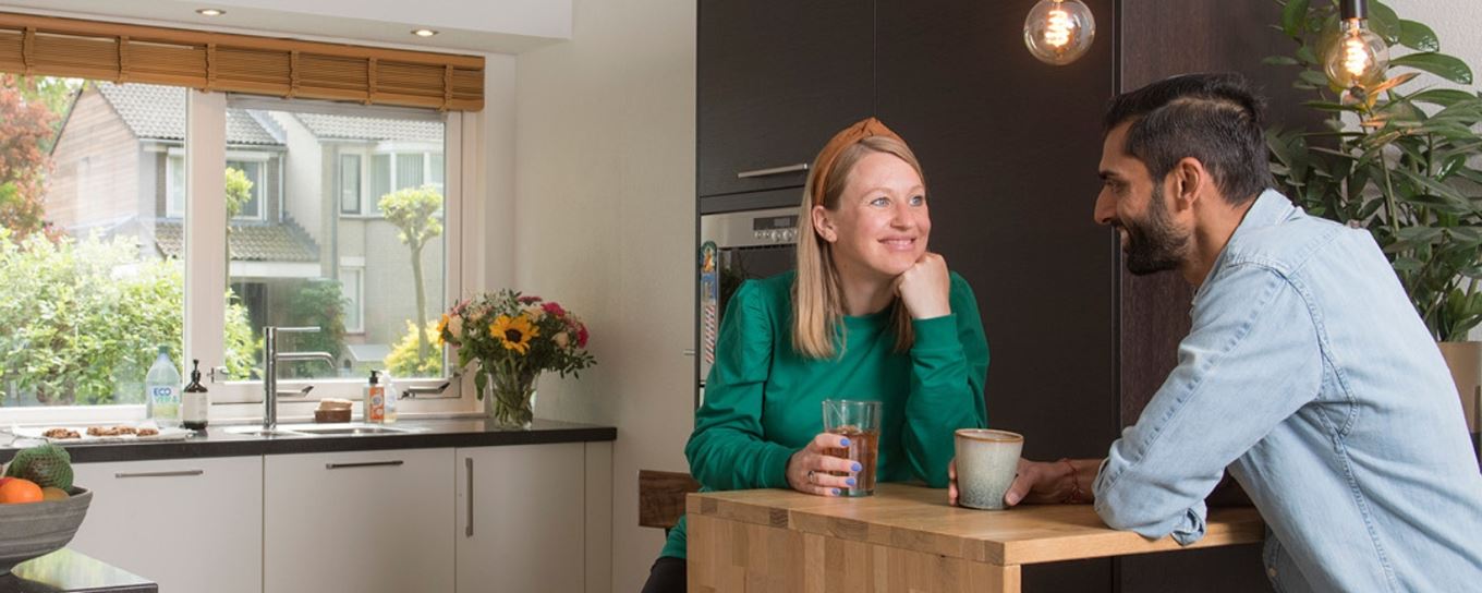 man en vrouw drinken een kopje koffie aan hun bar in de keuken