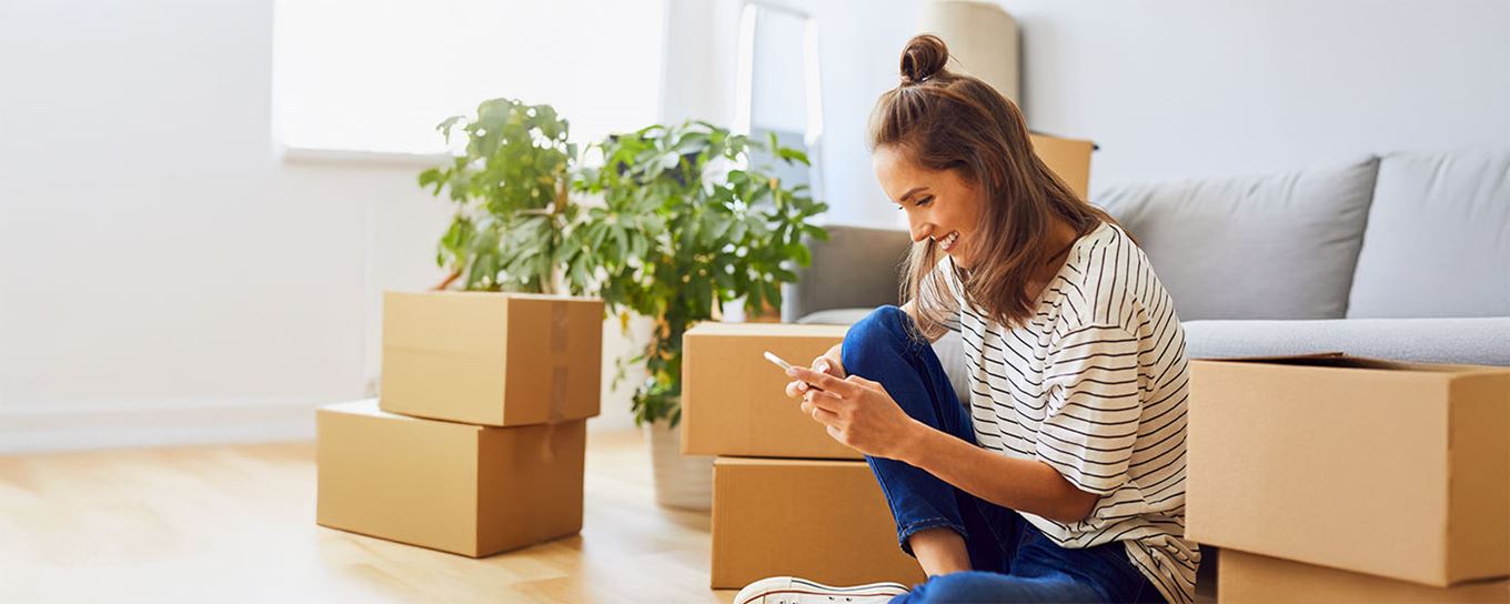 Een jonge vrouw met verhuisdozen om haar heen
