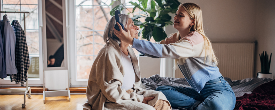 Oma en kleindochter luisteren samen muziek op bed