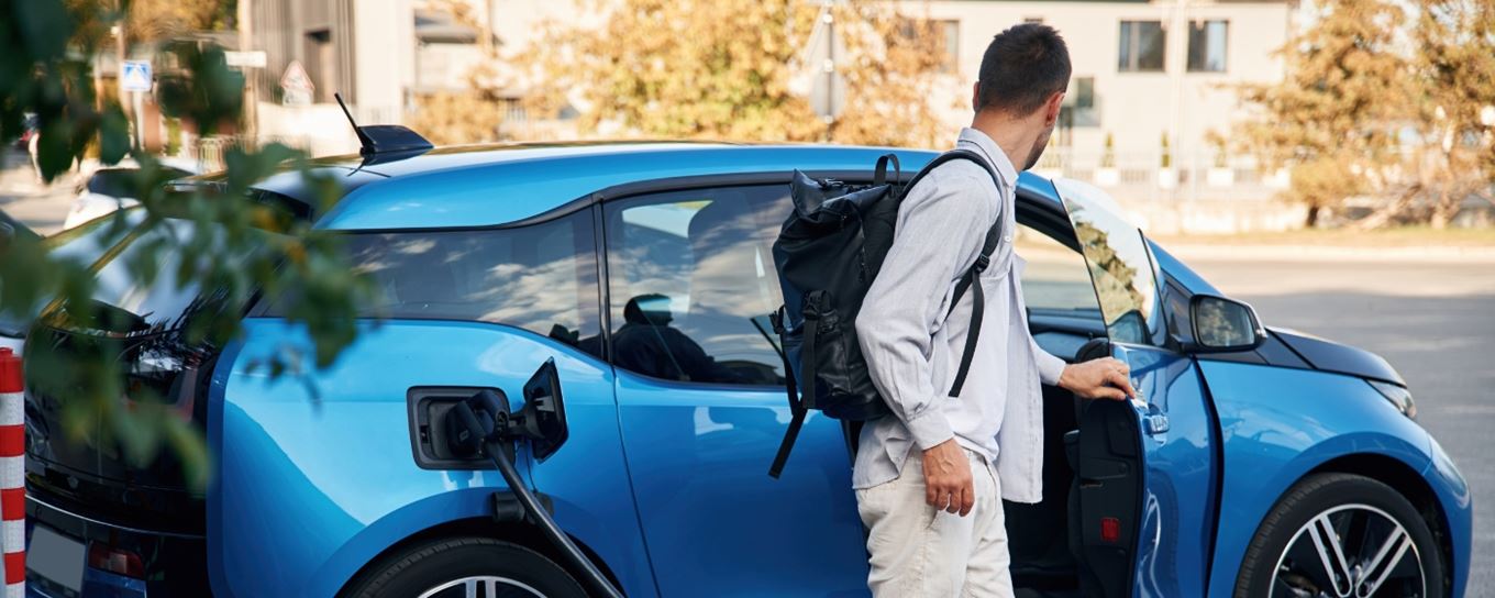 Afbeelding van een man bij een auto die aan het elektrisch opladen is