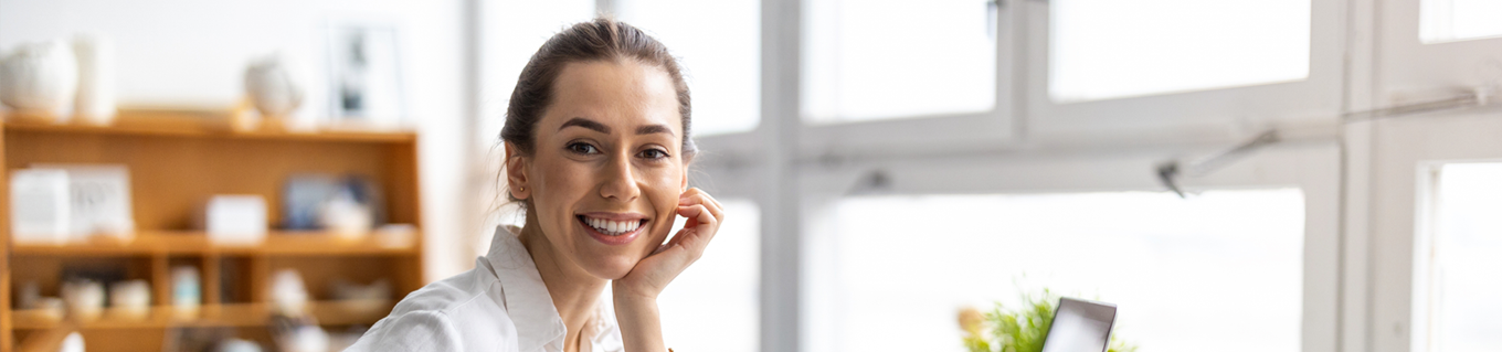 Vrolijke vrouw achter haar bureau kijkt in de camera | Doenpensioen | a.s.r.