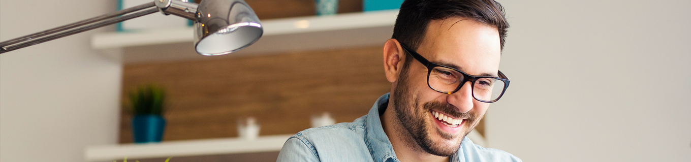 Man kijkt lachend naar zijn computer scherm| Doenpensioen | a.s.r.