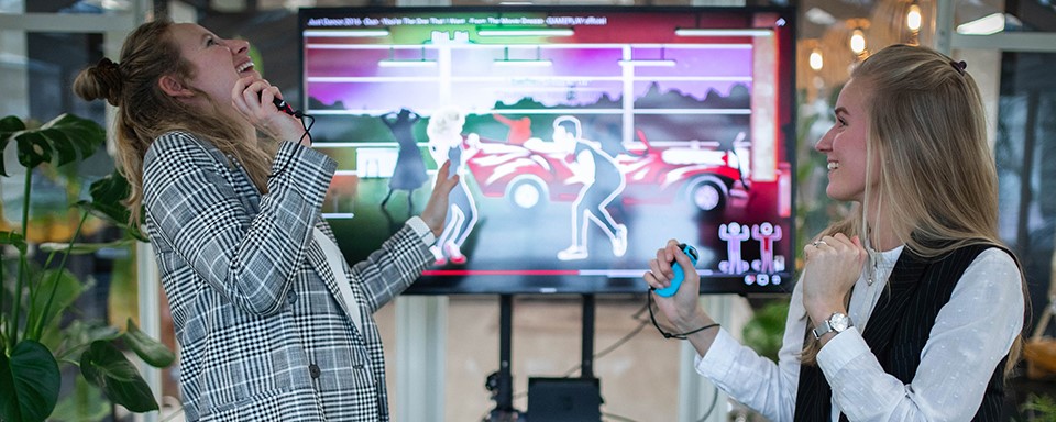 2 vrouwen spelen een bewegingsspel voor een groot scherm