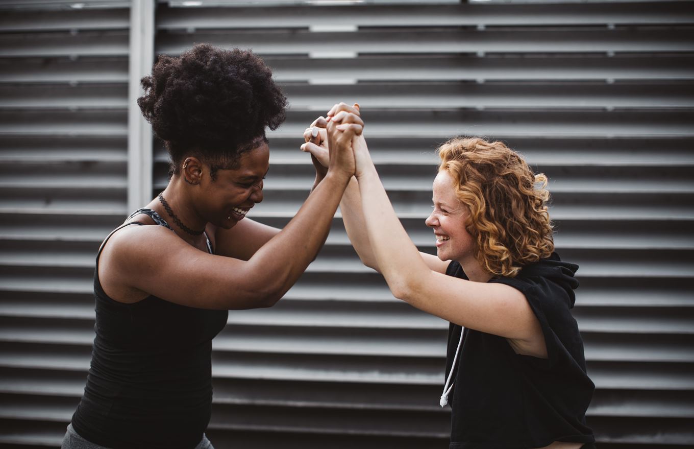 Lachende vrouwen houden handen omhoog